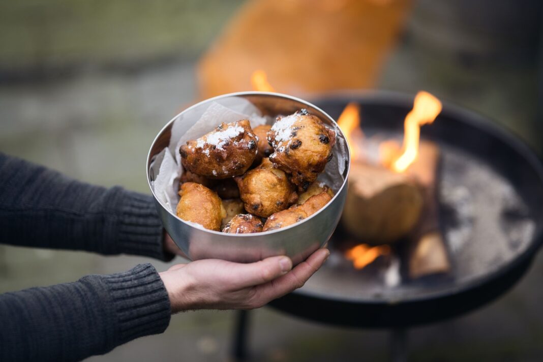 Miska domowych holenderskich oliebollen trzymana przy ognisku Miska domowych holenderskich oliebollen trzymana przy ognisku